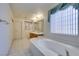 Bathroom featuring a soaking tub, dual sinks, and a large window at 5405 Lucky Clover St, Las Vegas, NV 89149