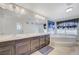 Bright bathroom featuring double vanity, large mirror, soaking tub, and natural light at 6205 Windy Oaks Ct, Las Vegas, NV 89139