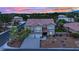 Striking two-story home with a three-car garage and desert landscaping at dusk at 7211 Heggie Ave, Las Vegas, NV 89131