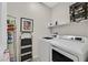 Well-lit laundry room equipped with modern washer and dryer units and storage shelves at 7910 Pearly Ct, North Las Vegas, NV 89084