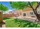 Landscaped backyard with artificial turf, a patio, seating area, and a mature shade tree at 10220 Adobe Mountain St, Las Vegas, NV 89178