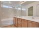 Bright bathroom featuring double sinks, wooden cabinetry, and a shower-over-tub combination at 10220 Adobe Mountain St, Las Vegas, NV 89178