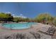 Sparkling blue community pool surrounded by lounge chairs and lush landscaping at 10220 Adobe Mountain St, Las Vegas, NV 89178