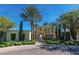 A beautiful clubhouse with a covered walkway, lush greenery, mature trees, and a brick-paved road on a sunny day at 10562 Cerotto Ln, Las Vegas, NV 89135