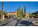 Community entrance featuring manicured landscaping, an arched entry, and decorative flags at 10562 Cerotto Ln, Las Vegas, NV 89135
