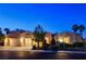 Exterior view of a desert home features a three-car garage and manicured landscaping under a dark blue sky at 10562 Cerotto Ln, Las Vegas, NV 89135