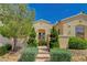 Lovely home featuring a front gate, mature trees, manicured bushes, and desert landscaping at 10562 Cerotto Ln, Las Vegas, NV 89135
