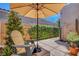 Desert patio with stone pavers, shade umbrella, and comfortable seating at 130 Twin Towers Ave, Las Vegas, NV 89123