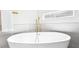 Close up of the modern soaking tub with gold fixtures, features horizontal window at 1343 Panini Dr, Henderson, NV 89052