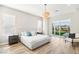 Bright bedroom with a light gray bed frame, modern chandelier, and view to the outdoor living space at 1343 Panini Dr, Henderson, NV 89052