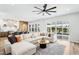 Bright living room with a white sectional sofa, ceiling fan, and sliding glass doors to the pool area at 1343 Panini Dr, Henderson, NV 89052