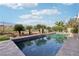 Sparkling blue pool surrounded by lush desert landscaping and black iron fence at 1343 Panini Dr, Henderson, NV 89052