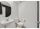This half bath has a pedestal sink, round mirror, and a neutral color palette at 1388 Graphite Ave, Henderson, NV 89002