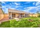A well-manicured backyard with artificial grass, a cozy covered patio, and a decorative flower bed, creating a serene outdoor space at 2561 Pyramid Pines Dr, Henderson, NV 89052