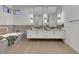 Bright bathroom featuring a soaking tub, double vanity sinks with dark fixtures, and neutral decor at 2621 Spalding Dr, Las Vegas, NV 89134