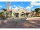 The house exterior featuring arched window and desert landscaping with rocks, turf, and palm trees at 2621 Spalding Dr, Las Vegas, NV 89134