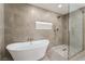 Contemporary bathroom featuring a soaking tub with gold fixtures and a glass enclosed walk-in shower with stone tile at 2909 Gilmary Ave, Las Vegas, NV 89102