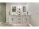 Bathroom featuring a dual sink vanity with lit mirrors, stone countertops, and a marble tiled walk-in shower at 2909 Gilmary Ave, Las Vegas, NV 89102