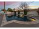 Backyard pool and patio area with a slide and lush landscaping, illuminated at dusk at 2909 Gilmary Ave, Las Vegas, NV 89102
