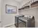 Modern laundry room with stainless steel washer and dryer and shelving above at 3179 Mura Del Prato Ave, Henderson, NV 89044