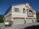 Home exterior showing a three-car garage, balcony, neutral stucco, and desert landscaping at 3208 Regal Swan Pl # 3, North Las Vegas, NV 89084