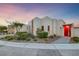 Modern home featuring a red door and desert-style landscaping with shrubs and decorative rock at 383 Solitude Peak Ln, Henderson, NV 89012