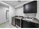 Modern laundry room with gray front load washer and dryer and dark cabinets with a sink at 383 Solitude Peak Ln, Henderson, NV 89012