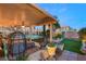 Covered back patio featuring comfortable seating and a view of the lush, landscaped backyard and pool at 3950 Candleglow Ct, Las Vegas, NV 89147