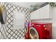 Modern laundry room featuring a striking patterned wall, white cabinets and a red washer and dryer at 3950 Candleglow Ct, Las Vegas, NV 89147