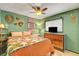 Cozy bedroom featuring green walls, wood accents, and eclectic decor, illuminated by a ceiling fan light at 5019 Lancaster Dr, Las Vegas, NV 89120