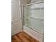 Clean bathroom featuring a tub with shower, glass doors, and shelving for toiletries at 5627 Spanish Valor Rd, Las Vegas, NV 89135