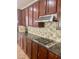 A kitchen boasts sleek granite countertops, mosaic tile backsplash, and dark wood cabinets with stainless steel appliances at 5627 Spanish Valor Rd, Las Vegas, NV 89135