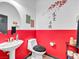 Half-bathroom with red accent wall, modern toilet and sink and artistic wall decor at 6324 Desert Leaf St # 3, North Las Vegas, NV 89081