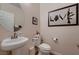 Stylish half bath with a pedestal sink, toilet, and unique art at 6750 Quapaw St, Las Vegas, NV 89149