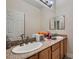 Bathroom features double sinks with granite counters, a large mirror and wood cabinets at 6750 Quapaw St, Las Vegas, NV 89149
