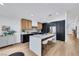 Modern kitchen featuring an island with seating, black and wood cabinets, stainless steel appliances, and wood floors at 679 Riverband Pl, Henderson, NV 89052