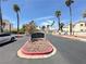 Inviting community entrance with lush landscaping, mature palm trees, and clear blue skies at 698 S Racetrack Rd # 322, Henderson, NV 89015