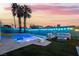 Inviting backyard featuring a pool, lush lawn, palm trees, and comfortable seating around a modern fire pit at 7018 Berkshire Pl, Las Vegas, NV 89147