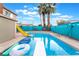 Backyard pool features a diving board, in-pool floats, privacy fence and palm trees at 7018 Berkshire Pl, Las Vegas, NV 89147