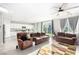 Bright living room featuring tile floors, ceiling fan, and comfortable seating adjacent to a modern kitchen at 7733 Rosebark Cliffs St, North Las Vegas, NV 89084
