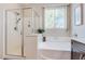 Bright bathroom showcasing a shower with a glass door and a large soaking tub under a window at 8232 Silver Vine St, North Las Vegas, NV 89085