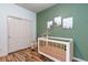 Bedroom featuring a crib, closet with sliding doors, and wood-look flooring at 8232 Silver Vine St, North Las Vegas, NV 89085