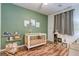 Bedroom with charming decor, featuring a crib, accent wall, and wood-look flooring at 8232 Silver Vine St, North Las Vegas, NV 89085