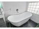 Bathroom featuring freestanding tub, dark tile floors, and modern fixtures at 8504 W Gilmore Ave, Las Vegas, NV 89129