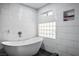 Bathroom featuring a freestanding tub, subway tile, and a glass block window at 8504 W Gilmore Ave, Las Vegas, NV 89129