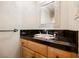 Half bathroom featuring a decorative mirror, wood vanity and black tile countertop at 9000 Opus Dr, Las Vegas, NV 89117