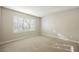 A carpeted empty bedroom with a large window and neutral walls is ready for your personal touch at 9000 Opus Dr, Las Vegas, NV 89117
