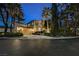 Beautiful two-story home with a well-manicured lawn and mature trees at twilight at 9000 Opus Dr, Las Vegas, NV 89117