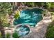 A beautiful custom pool with a spa and rock waterfall feature is surrounded by mature landscaping at 9000 Opus Dr, Las Vegas, NV 89117