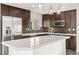 A spacious kitchen featuring dark wood cabinets, stainless steel appliances and a white countertop island at 10525 Shiny Skies Dr, Las Vegas, NV 89129